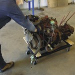 Man moving engine on dolly.