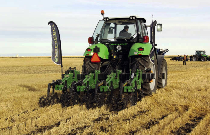 Tractor and implement working a field.