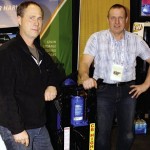 Two men standing beside hydraulic lift.