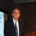 Man standing on stage making presentation.