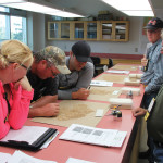 Farmers and grain marketers attending a recent one-day workshop at Olds College look over a sample of Hard Red Spring wheat to determine how much mildew damage appeared in the sample and then decide whether it Graded No. 1, No. 2, or No. 3. Bill Adduono (r), green shirt, an operations supervisor with the Canadian Grain Commission provided directions and advice on the visual grading process which is anything but clearcut.