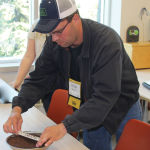 Farmer Kevin Sandau collects a sample of canola seed at a grain grading workshop which he later crushed with a roller and then compared to the official Canadian Grain Commission colour chart to estimate the amount of green seed in the sample.