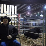 Vernon Davidson sips coffee while his bull, Davidson Walker, relaxes behind him.