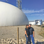 Christina and Andy pose beside Crowfoot Ag Solution’s fertilizer dome. The dome is a storage and blending facility.