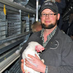 Walter Decker, egg barn manager at the Riverbend Hutterite Colony at Mossleigh, south of Calgary with one of the laying hens in their new barn outfitted with an enriched cage system.