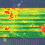 This is what is known as an NDVI image (normalized difference vegetation index) of an on-farm, field-scale soybean trial. This trial, with different treatment strips across the field, was looking at using a pre-seeding herbicide, such as a granular which was incorporated, compared to a glyphosate treatment. In some areas where the pre-seeding product was ineffective they went back in with an in-crop herbicide treatment which in some areas damaged the crop. The mostly green area is a relatively healthy crop with the strips indicating different treatments. The red areas show problems in the field. The headlands may indicate a different crop or different type of vegetation, or higher compaction. The larger red patches on the upper left hand side show areas that have likely been flooded out or have a disease problem. The yellow areas indicate crop that has been damaged by in-crop herbicide. There is a powerline or pipeline right away cutting diagonally across the upper right hand side of the photo.