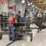 Riding on a carrier to move it forward, the basic chassis is bolted together at the start of the swather assembly line. 
