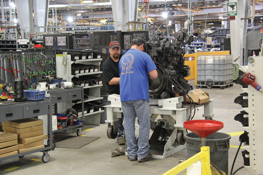 Employees ready the engine and transmission for installation. 