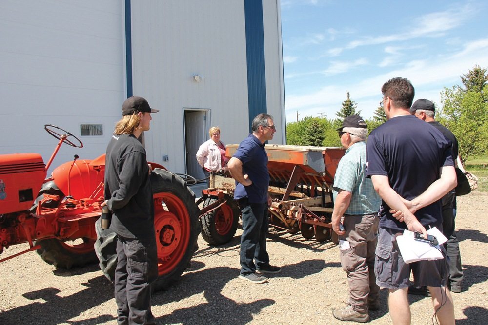 Greg, Cheryl, and Andrew Herle show reporters some vintage farm equipment, which still comes in handy for seeding small plots.