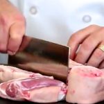 Chef Jonathan Collins cuts up a pork leg, foot included, to prepare ginger and black vinegar hog trotters in a video for Canada Pork International. (Video screengrab from CanadaPork.com)