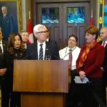 International Trade Minister Jim Carr (at podium) and Agriculture Minister Marie-Claude Bibeau announce plans for a technical delegation and stakeholder working group to address China’s import bans on Canadian canola. (AAFC video screengrab via Facebook Live)