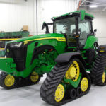 John Deere’s 9R family of tractors continues to offer articulated wheeled, two- and four-tracked models from 370 to 620 engine horsepower. But in 2019 there was big news from the green brand about other model ranges it offers in the high horsepower segment. The company unveiled the results of a major revamp to its 7R and 8R tractor families that includes new styling, rejigged engineering and, most notably, an industry first with the new 8RX line.
The 8RX models are the first rigid-frame tractors to roll out of a factory riding on four rubber track modules. Four models make up the 8RX Series, which span the 310 to 410 horsepower range. (In fact all models in the 8R line will get a boost up to 410 horsepower.) And these aren’t just regular 8R models with bolt-on track systems. The drivelines in these tractors have been engineered specifically for tracks. That includes completely new axles that can handle the added torque.
Those axles make the 8RX tractors stand a couple of inches taller than their other brothers in the 8 Series. And at the top of that higher cab roof is a built-in GPS receiver, a feature that will appear on all 7R and 8R tractors for the 2020 model year.
Riding on four tracks means wheel slip will be very low, because of the extra traction those rubber belts create. So there isn’t a need for a lot of ballasting. The tractors weigh in at around 41,000 pounds on up to about 44,500. And there won’t be much of a range to increase it.
There will be a choice of axle spacing up to 120-inches, so it will accommodate any row-crop needs. The rubber belts will be offered in 18-, 24- and 30-inch widths. But the 30-inch tracks are only available on the back of the machine.
While Deere engineers confirm the company has used a variety of components from its 9RX driveline systems, it isn’t just a blend of off-the-shelf components, the drivelines were tailored specifically for the 8RX.
Deere has given the four-track 8RX tractor line new styling as well as new engineering. And the new look will transfer to all 8R and 7R models as well.
Along with the new look comes new model numbering. The family designation (8) and the series (RX) will now appear near the front of the hood. The engine horsepower rating stands alone a little farther back along the side.
Overall, the 8R line now has seven models available from 230 to 410 engine horsepower, while the 7Rs will now be available in seven models from 210 to 330. So in that overlap area there are several models in both ranges to choose from.
Finally, Deere has made it easier for owners to do their own diagnostic work on these tractors, which is a result of criticisms levelled at all brands in the right-to-repair debate that has raged mostly in the U.S.