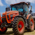 “We’re not here as a flavour of the month,” Bob Hickey, president of Kubota Canada told the brand’s dealers at the introduction of the new M8 tractor line in Texas in July, 2019. And all the messages telegraphed by management at that event clearly indicate Kubota intends to keep driving toward a fuller market share in the ag equipment sector. The M8 tractor line is a key step in that direction.
The two new tractors that make up the M8 Series take up where the M7s leave off. (The M7s top out at 168 engine horsepower.) There are two models: the 190 engine horsepower M8-191 and 210 horsepower M8-211. These tractors will, as expected, share a base platform with Versatile’s Nemesis line and will be built for Kubota in Winnipeg at Versatile’s assembly plant.
A 6.7-litre Cummins will supply the muscle that can be routed through a fully electronic 30x15 power shift transmission, which includes a shuttle shift with either a 40 or 50 km/h. top speed. Or the tractors can be equipped with an optional 50 km/h.-capable CVT. The powershifts offer six on-the-go gear changes in each range. And the transmission will auto shift up to a pre-set speed as well as downshift when the engine lugs down to a pre-set limit, making this a simple tractor to operate.
These MFWD tractors can be equipped with a rigid or suspended front axle. The suspended-axle versions also get cab suspension to significantly soften the ride for an operator.
At the rear, a 540 or 1,000 r.p.m. PTO can be operated in both standard and eco modes. A 1¾-inch, 20-spline shaft is also available as an option. Three-point hitch lift capacity is 5,660 kilograms, but that can be raised to 7,050 as an optional feature.
A hydraulic flow rate of 120 l/min. is standard, but that can be boosted up to an optional 160. Three rear remotes are standard, with five as an option there.
With 148 cubic feet of interior space, the cab is larger than the M7’s, but the control armrest is identical. Inside the cab, a seven- or 12-inch LCD touch screen monitor is fully ISOBUS compatible, allowing the tractor to maximize communication with any compatible implement from any brand. Built into the tractor’s brain is a customizable headland control feature to automate turns in the field. And Kubota has decided to use an open architecture system to make the tractor compatible with any GPS auto-steer system currently on the market.
Kubota will also allow buyers to pair an M8 with the new self-levelling M77 front-end loader, which includes shock-absorbing hydraulic accumulators that cushion the tractor and loader arms from hard shocks when going over rough terrain.
The joystick that controls the loader has a third-function feature that allows for grapple control. And there is even a fourth function available as an upgrade. The M77 loader has a 2,360-kilogram load rating at maximum lift height and a breakout force rating of 4,600 kilograms. So these tractors offer capacities well beyond what most utility category tractors can offer.