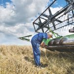 farmer repairing combine harvester