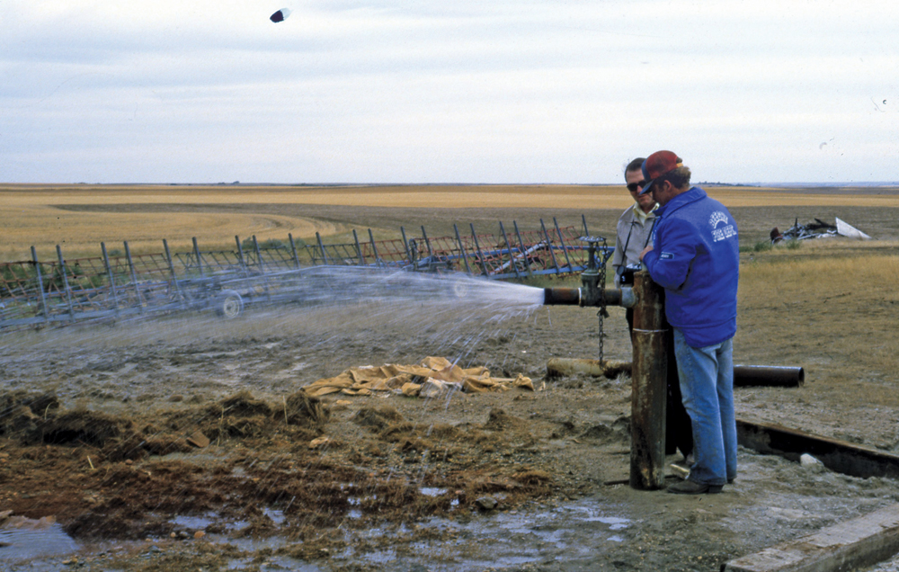 Bill Meneley (wearing sunglasses) checks out a flowing well on the farm of Gerry Wiens of Beechy, Sask.