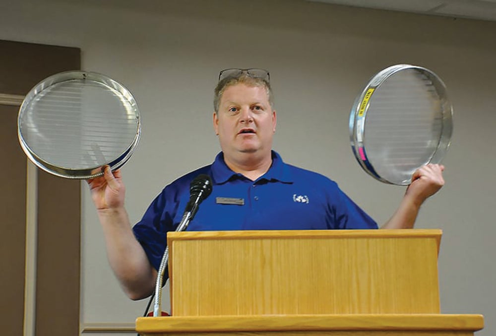 Joey Vanneste of the CGC shows farmers at a Swift Current, Sask. seminar two types of sieves used in the official grain grading process.