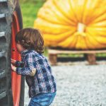small child peering into hub of back tractor wheel