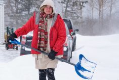 A woman digging out her driveway after a big snowstorm