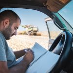 Farmer manage harvesting process, he is concentrated and writing corn quality on field.