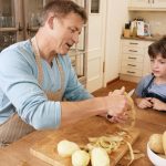 dad peeling potatoes while son watches