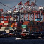 A tugboat passes shipping containers being unloaded and stacked on a pier at Port Newark, New Jersey, U.S., November 19, 2021.
 Photo: Reuters/Mike Segar/File