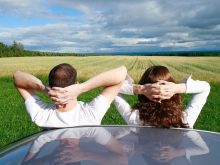 Young Couple Leaning on Car overlooking Farmland, Ile D'orleans, Quebec