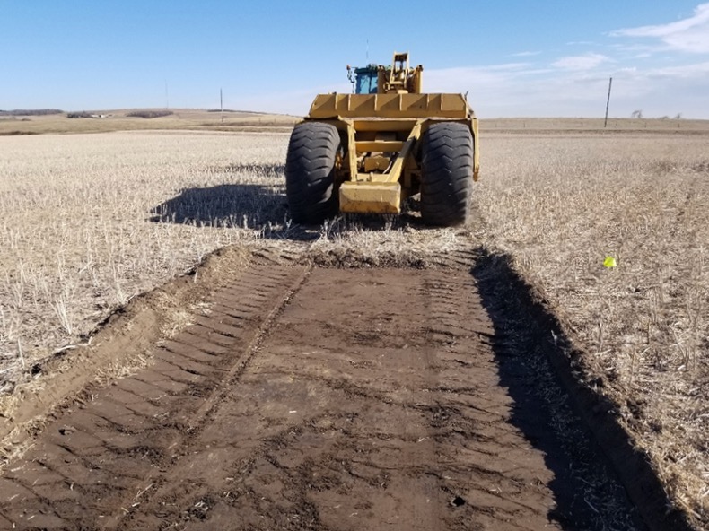 Topsoil being removed from a depression area in a soil landscape restoration site in southern Manitoba.