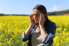 woman with headache in canola field