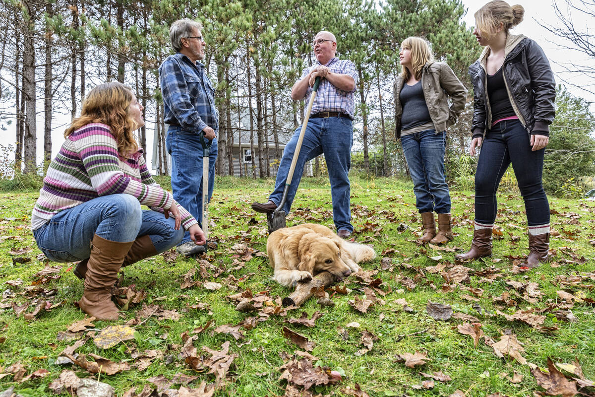 A neighbor stops to tell a story to a father and his three daughters a their dog on a fall day. TerryJ/E+/Getty Images