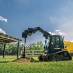 A yellow track loader at work on a rural acreage