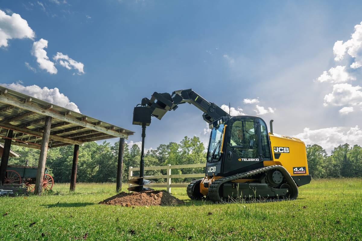 A yellow track loader at work on a rural acreage