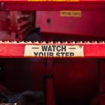 Close-up at metal steps part with anti-slip floor and caution sign of the working platform stairway. Industrial equipment object photo, selective focus.