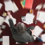 Accounting and processing a mess of stressful paperwork. Man doing challenging work with taxes, overhead shot with zoom blur effect