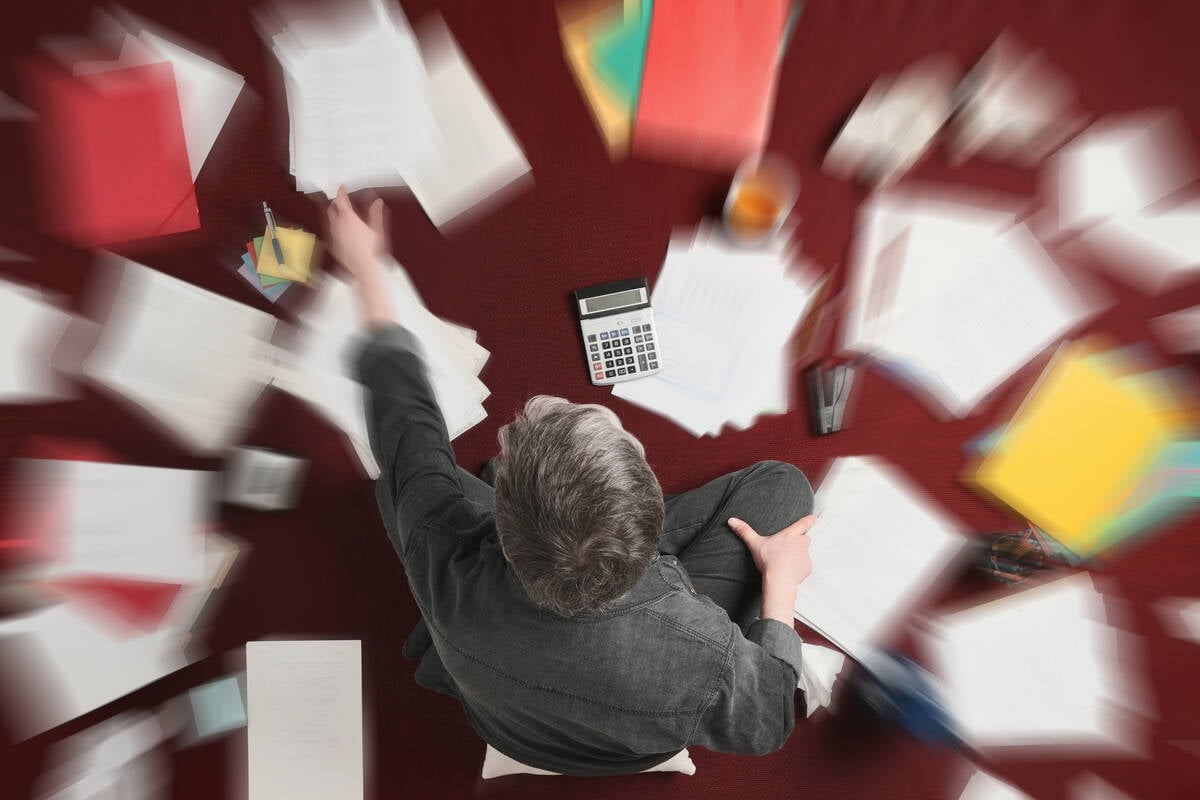 Accounting and processing a mess of stressful paperwork. Man doing challenging work with taxes, overhead shot with zoom blur effect