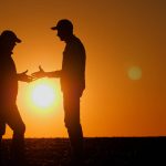 Firm handshake between two farmers in silhouette at sunset. Pic: StockSeller_ukr/iStock/Getty Images