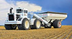 an oversized white tractor towing an equally large-scale white grain cart