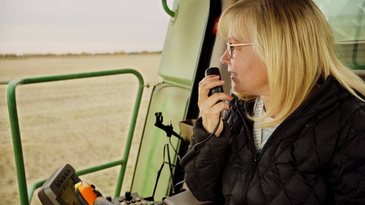 Close-up of a mature woman farmer sitting in combine harvester talking on a cb radio in farm field. Photo: AJ_Watt/E+/Getty Images
