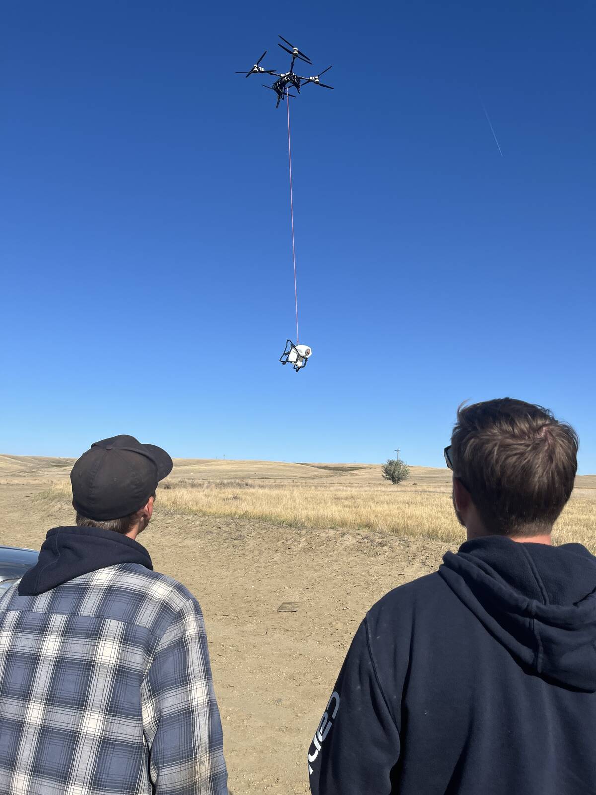 Tyler Torrie, left, of Riverview Ranch and Loren Ginn of Sky Drones witness the capabilities of the AGRAS T100 agricultural drone’s lifting capabilities during a demonstration on the ranch.