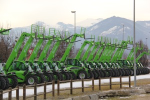 A line of telehandlers at the Merlo factory in Cuneo Italy stand with the Alps in the background.